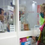 Kobieta w maseczce rozmawia z farmaceutą przy aptecznym okienku