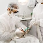 Dentysta z asystentką leczący zęby pacjenta w gabinecie
