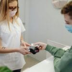 Recepcjonistka medyczna przyjmuje płatność kartą od pacjenta