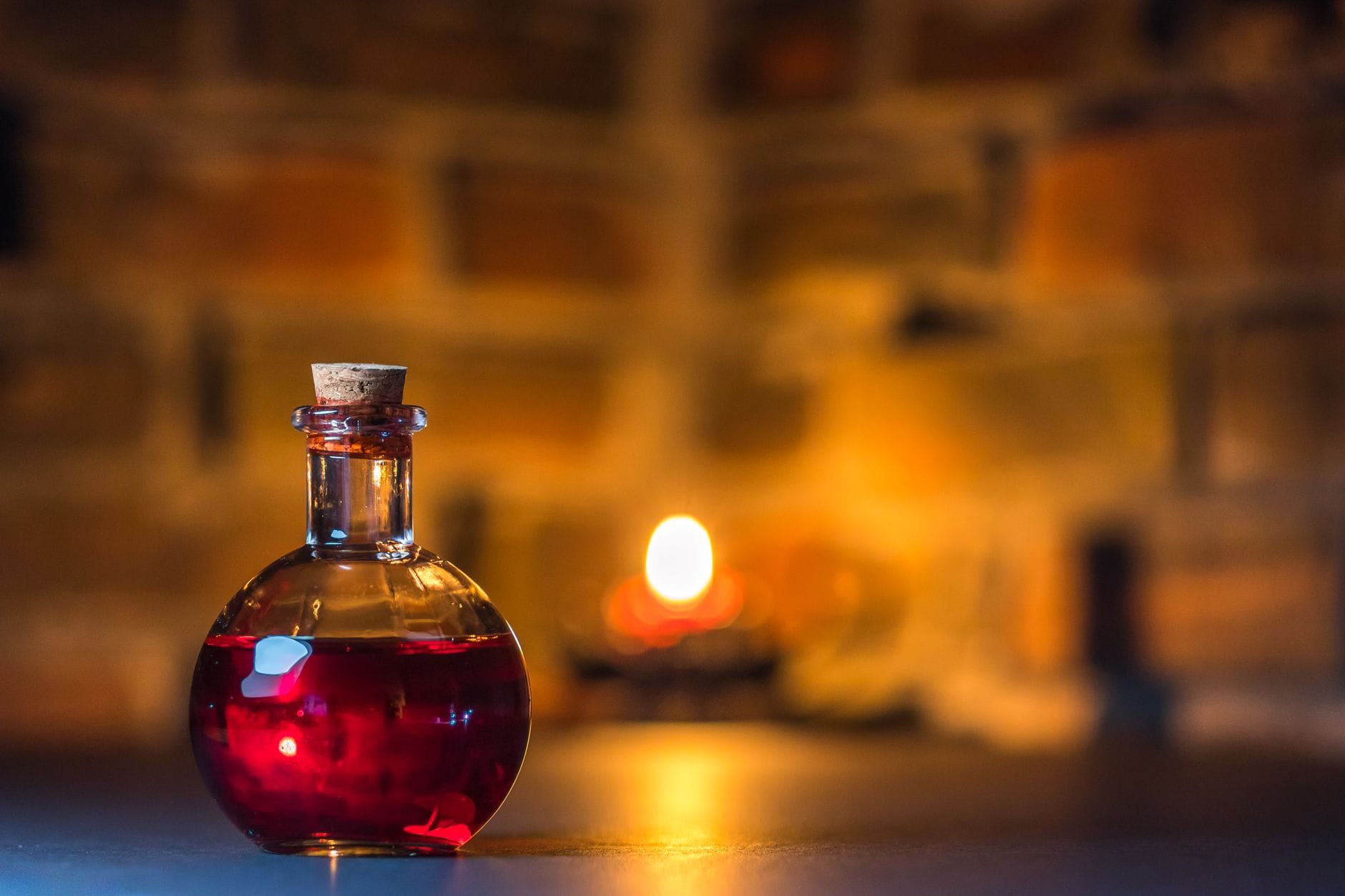 Butelka z magicznym eliksirem świecąca w blasku świec na tle ceglanej ściany
