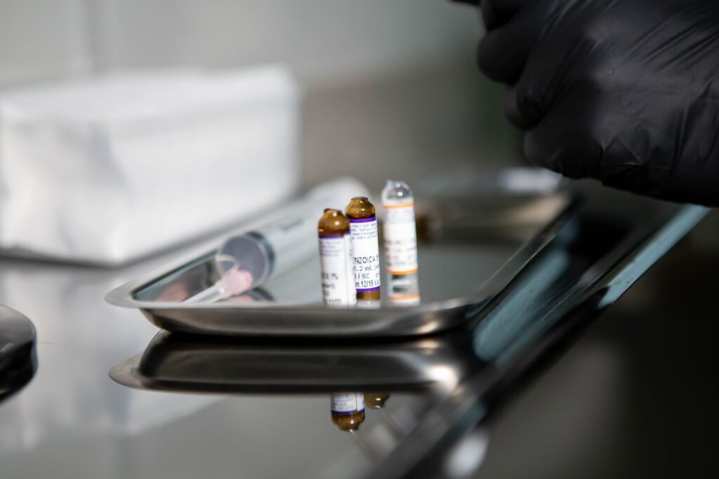 Fiolki medyczne i strzykawka na stalowej tacy klinicznej